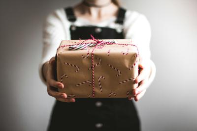 Image of a figure holding a wrapped present toward the camera